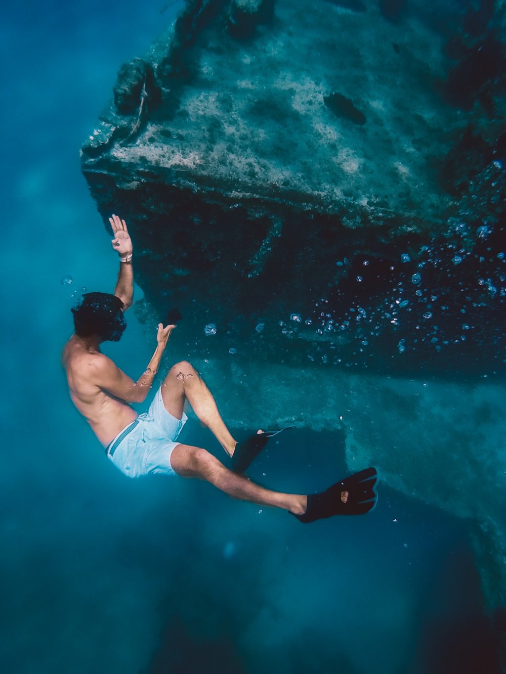 boy snorkels next to a ship wreck submerged in the ocean